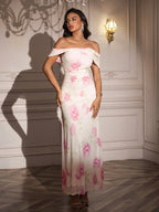 Woman with hands on hips in a white off-the-shoulder maxi dress with a pink floral print.