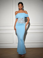 Front view of a woman in a flowing light blue evening gown featuring an off-the-shoulder design and delicate lace accents.