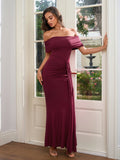 Model leaning against a doorframe in a burgundy off-the-shoulder ruched gown.