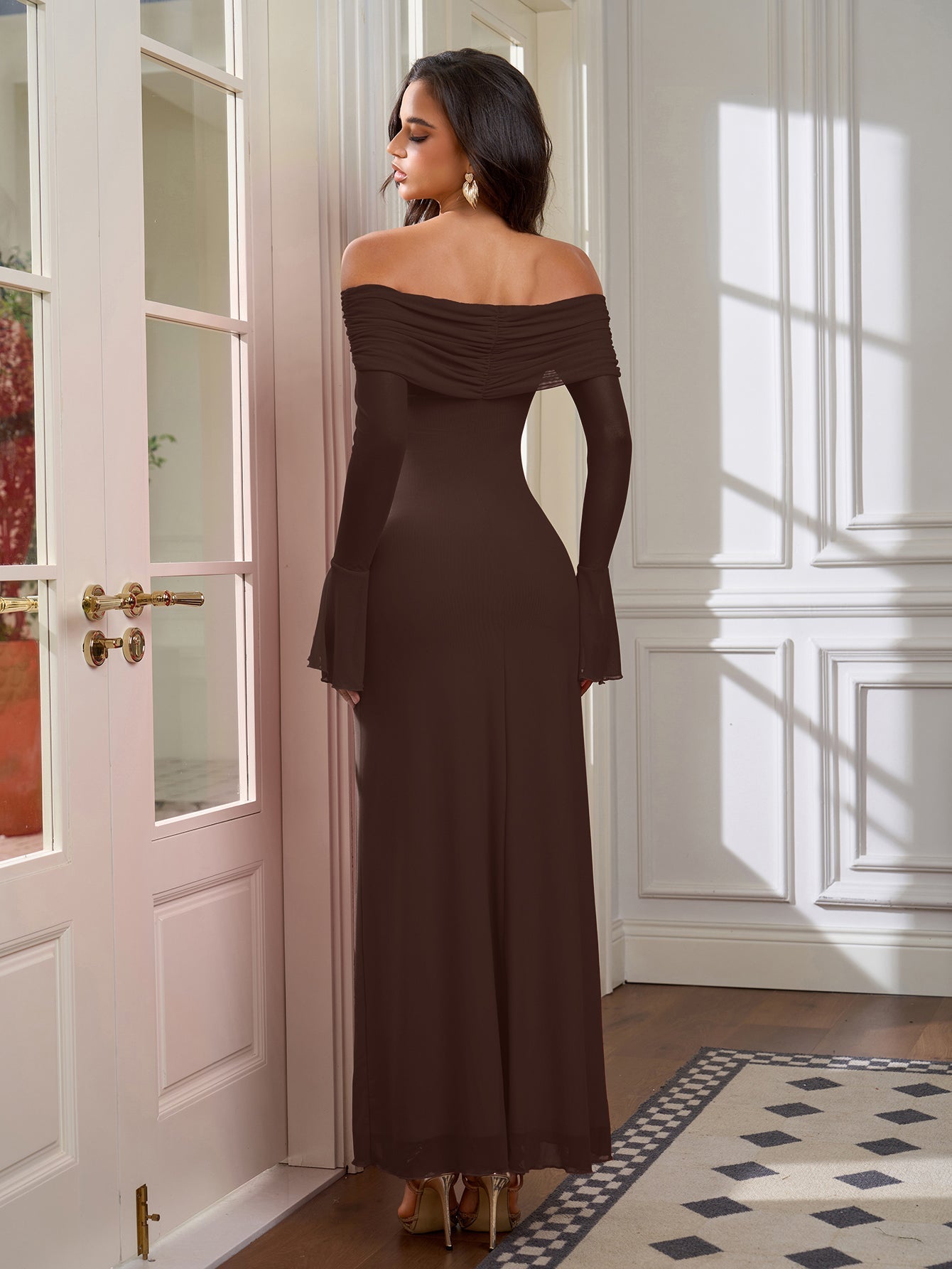 Back view of a woman in a long brown off-the-shoulder dress with flared sleeves