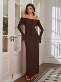 Woman standing by a doorway in a brown off-the-shoulder maxi dress
