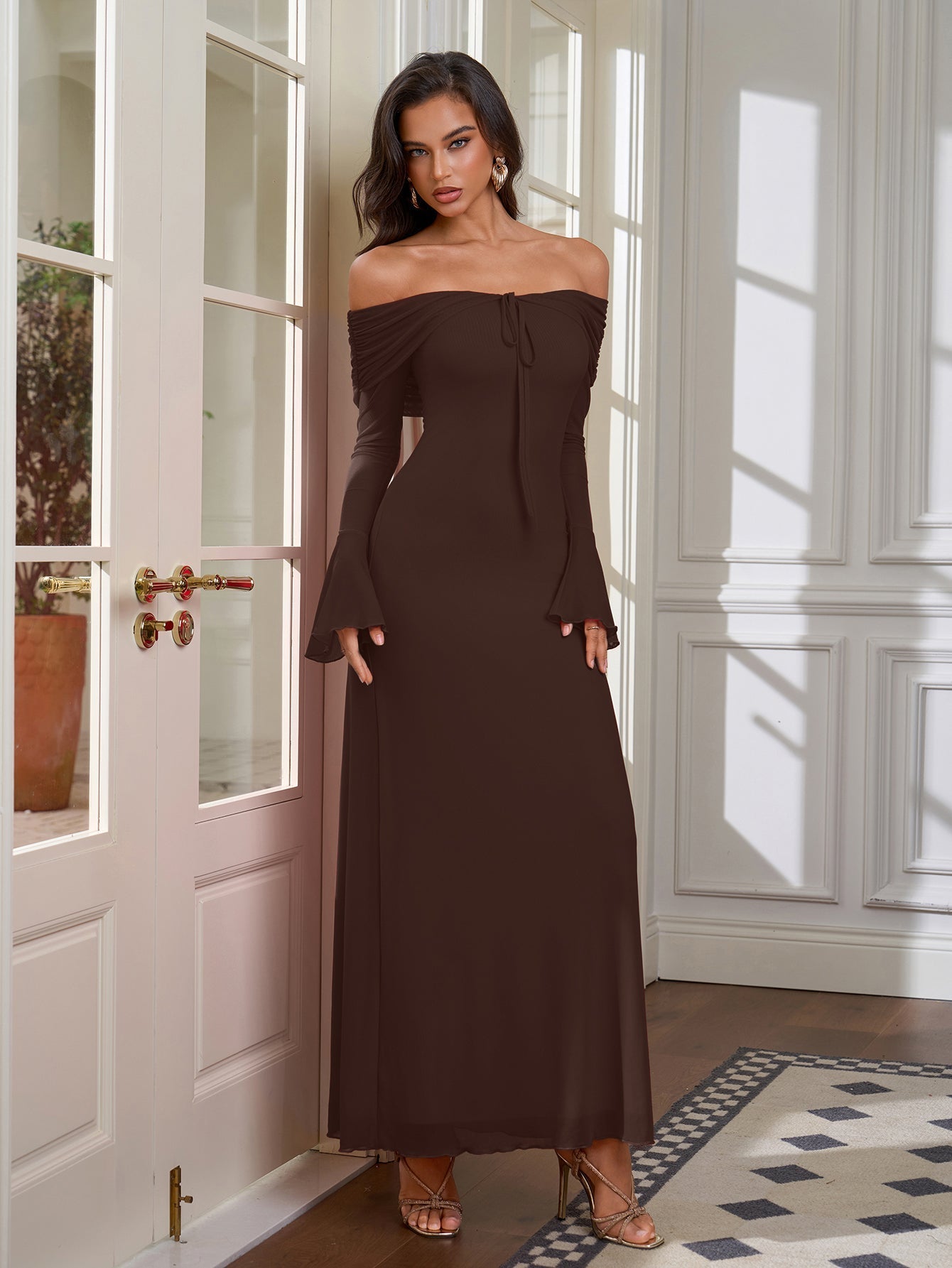 Model posing in a brown off-the-shoulder dress with long flared sleeves