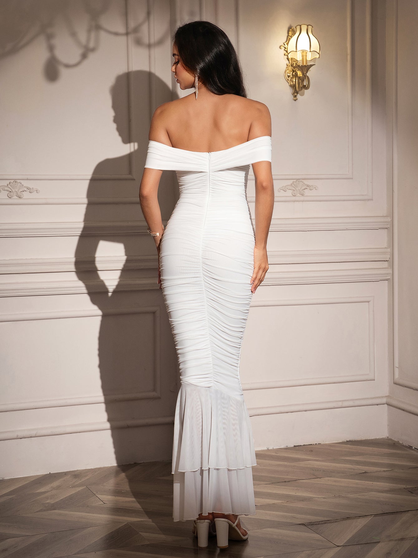 Back view of a woman in a white off-the-shoulder ruched mermaid gown