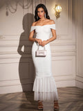 Woman wearing a white off-the-shoulder ruched mermaid gown with a ruffled hem