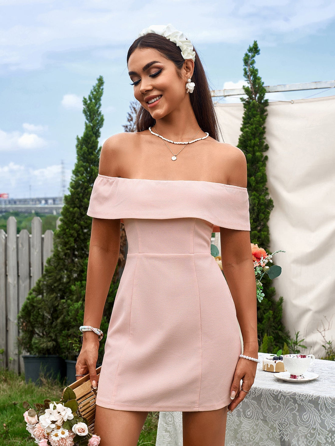 Woman wearing a pink off-the-shoulder mini dress outdoors