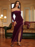 Woman wearing a purple velvet evening gown with an asymmetrical neckline, long sleeves, and a thigh-high slit with fringe.