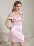 Full body shot of a woman in a pink satin mini dress with off-the-shoulder draped sleeves.
