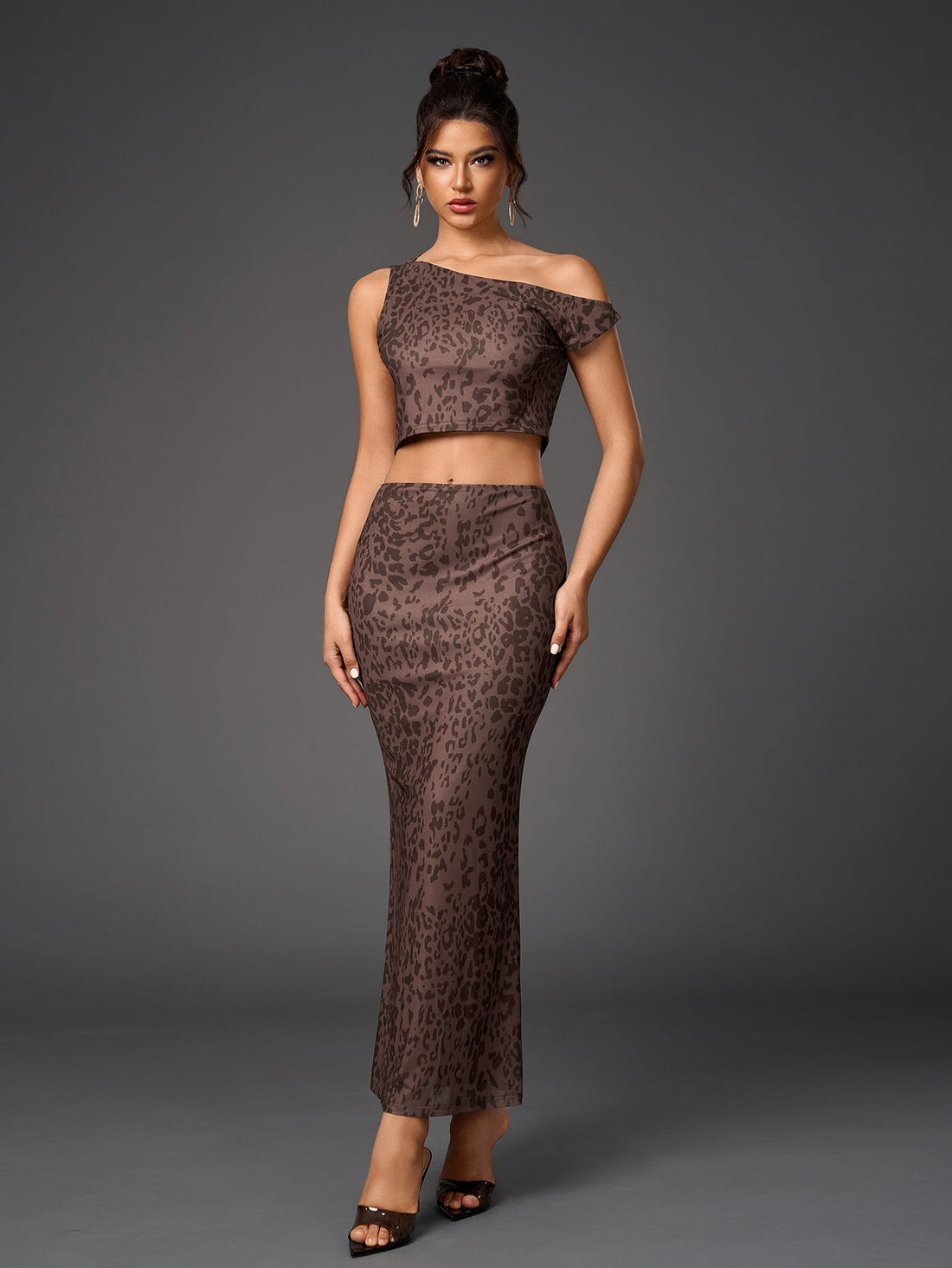 Woman wearing a brown leopard print sheer mesh two-piece set with a cropped asymmetrical one-shoulder top and a long fitted skirt.