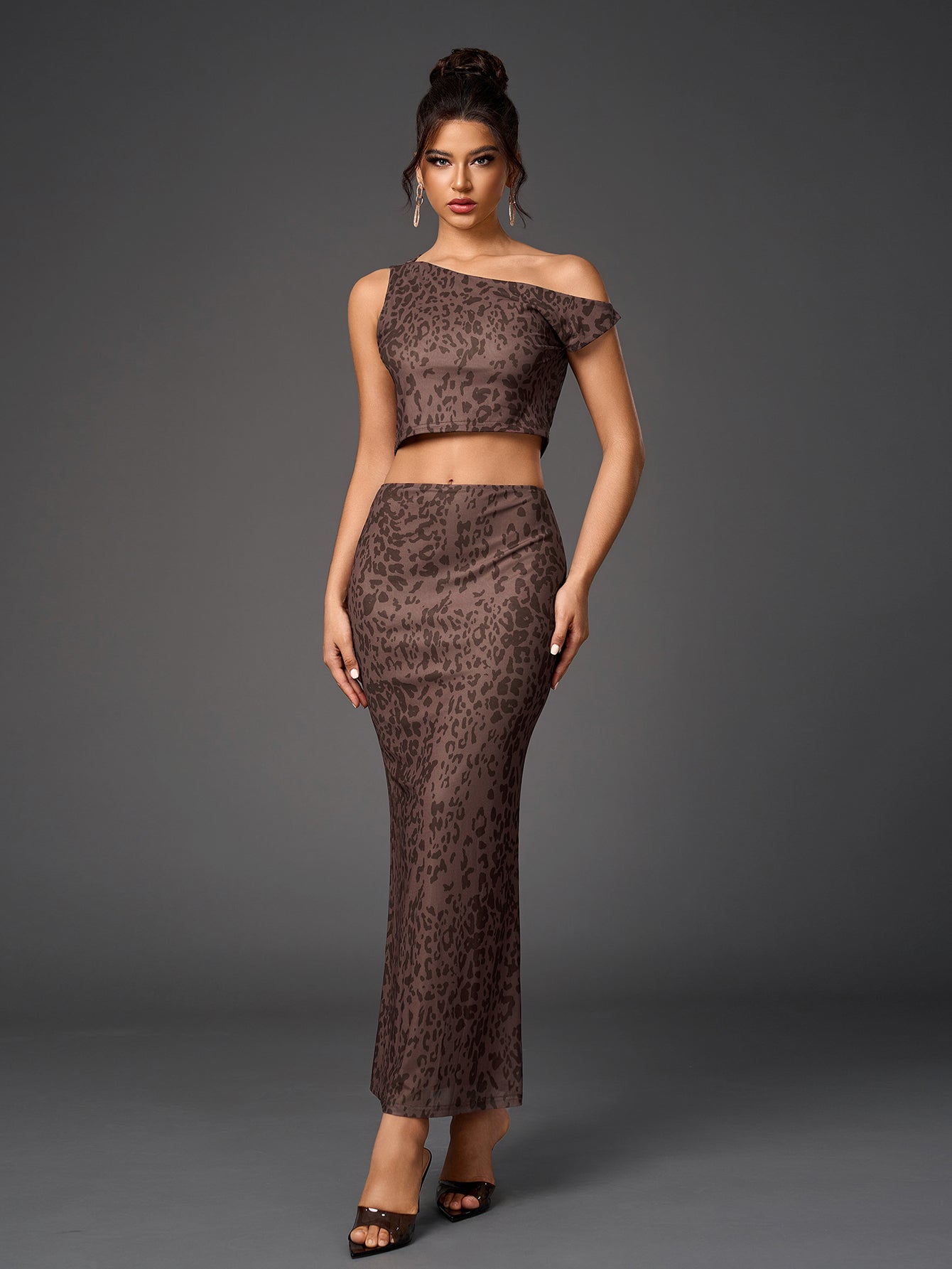 Woman wearing a brown leopard print sheer mesh two-piece set with a cropped asymmetrical one-shoulder top and a long fitted skirt.
