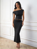 Woman wearing a black asymmetrical two-piece set with a cropped top and mermaid skirt