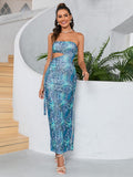Full-length view of a woman in a blue abstract print strapless maxi dress with a tie belt and cut-out details.