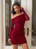 Woman wearing a burgundy ruched off-the-shoulder dress with sheer long sleeves
