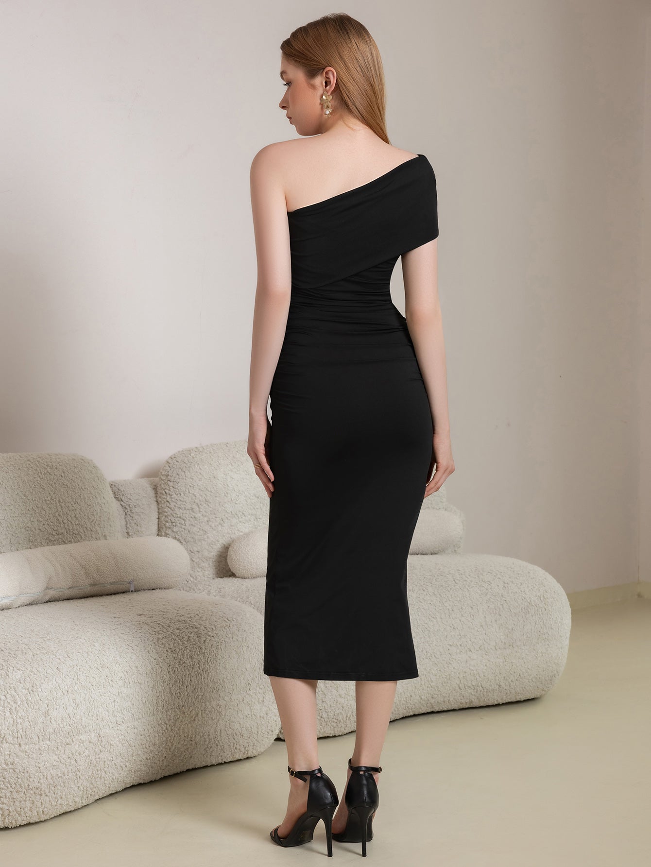 Back view of a woman in a black one-shoulder ruched sheath dress