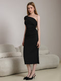 Model posing in a black asymmetrical neckline dress