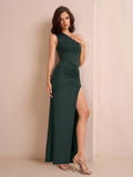 Woman posing in a dark green one-shoulder jersey knit column maxi dress with ruched detailing and a high slit
