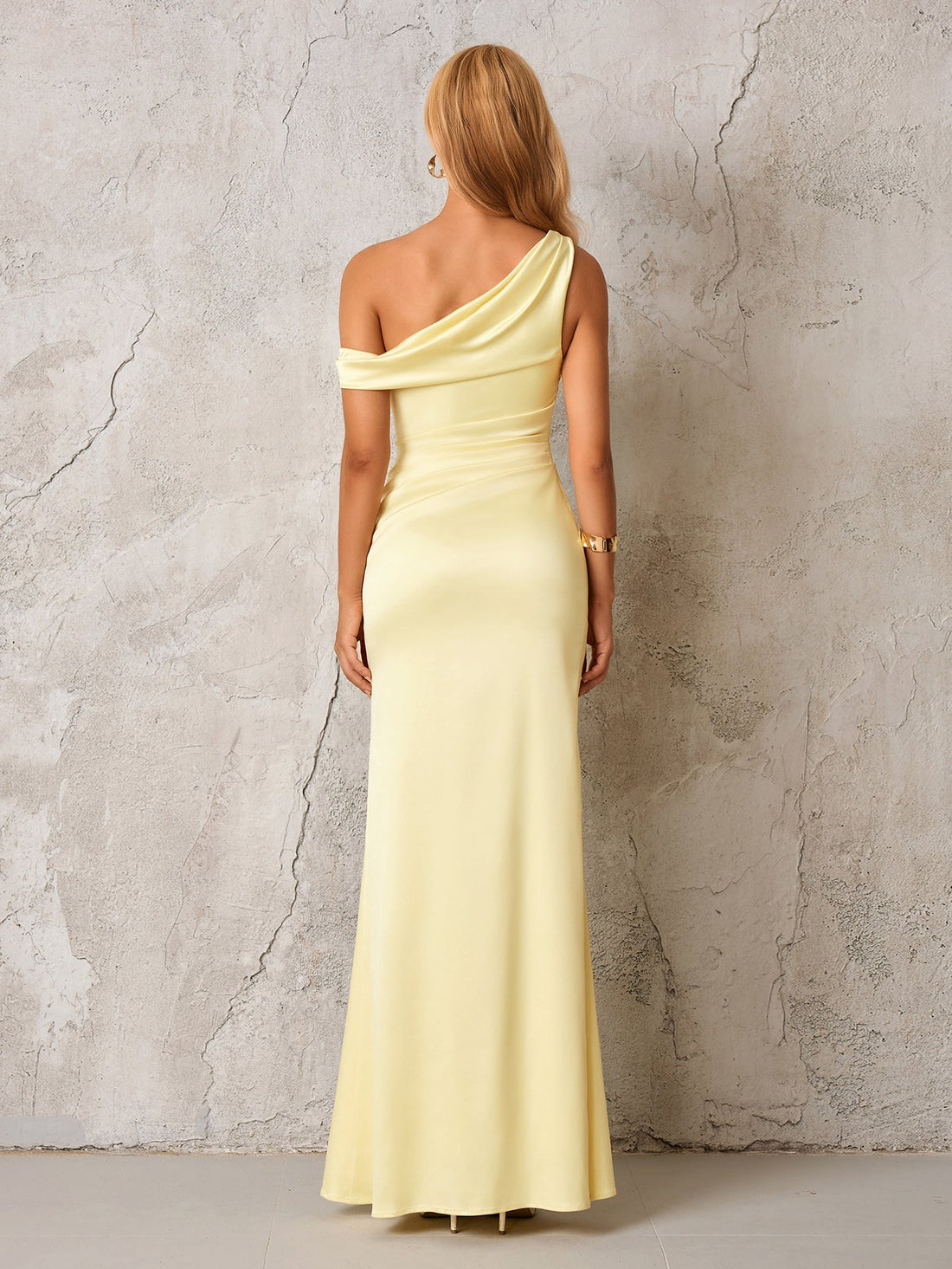 Woman wearing a pale yellow satin one-shoulder floor-length column dress with draping and ruching