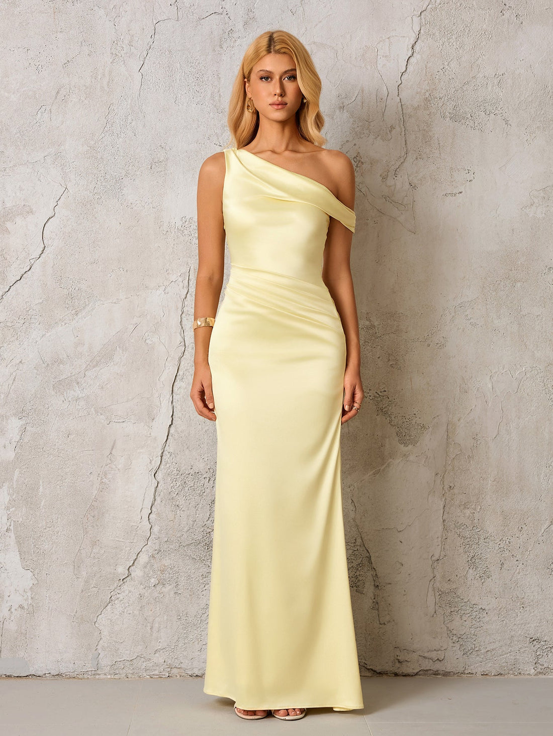 Woman wearing a pale yellow satin one-shoulder floor-length column dress with draping and ruching