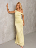 Woman leaning against a wall in a pale yellow satin one-shoulder floor-length column dress