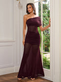 Woman wearing a burgundy one-shoulder ruched gown with sheer panels