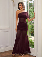 Woman wearing a burgundy one-shoulder ruched gown with sheer panels
