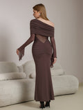 Back view of a woman in a long brown dress with flared sleeves and a V-shaped sheer panel