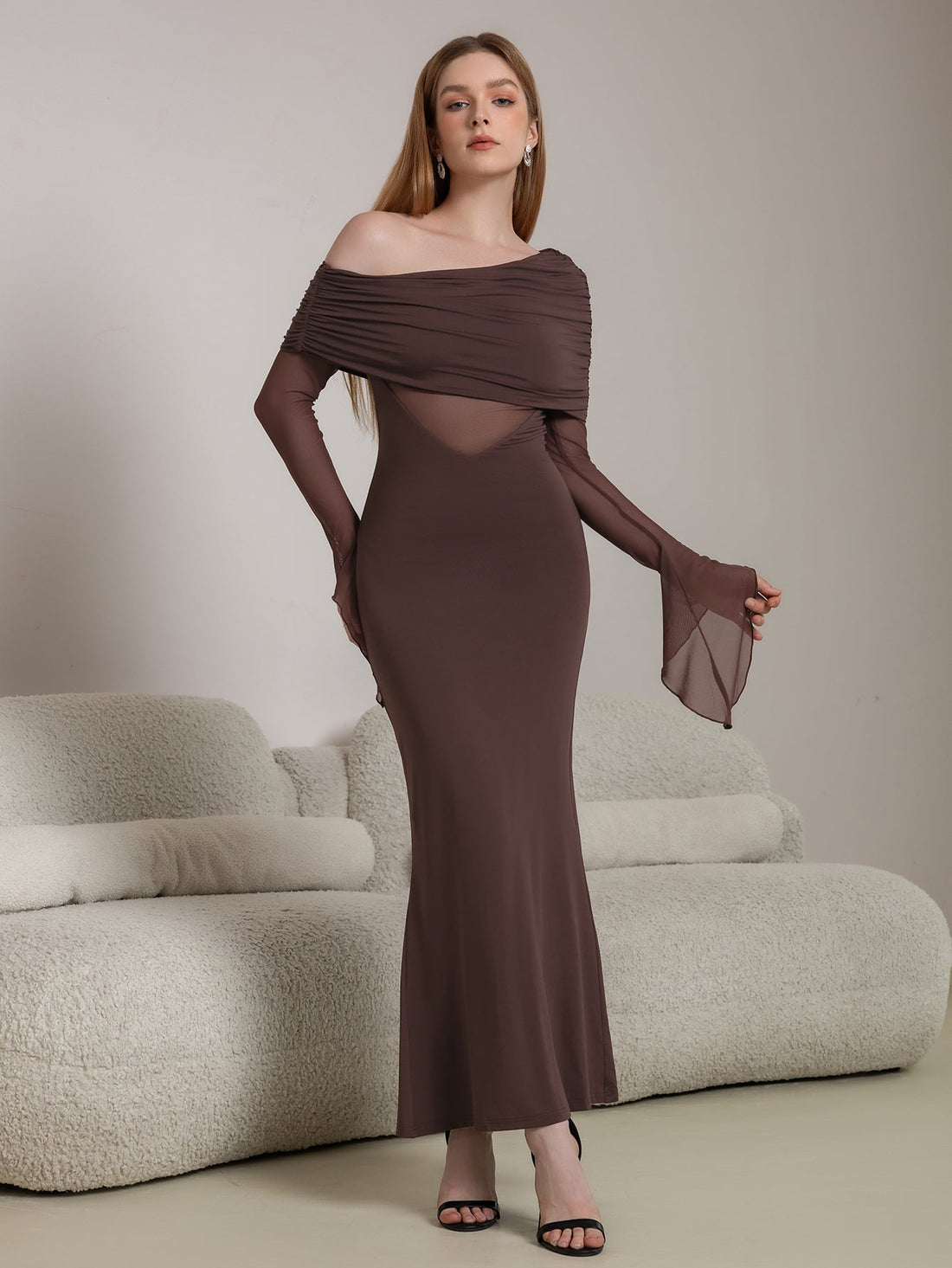 Woman wearing a long brown off-the-shoulder dress with ruched detailing and sheer paneling