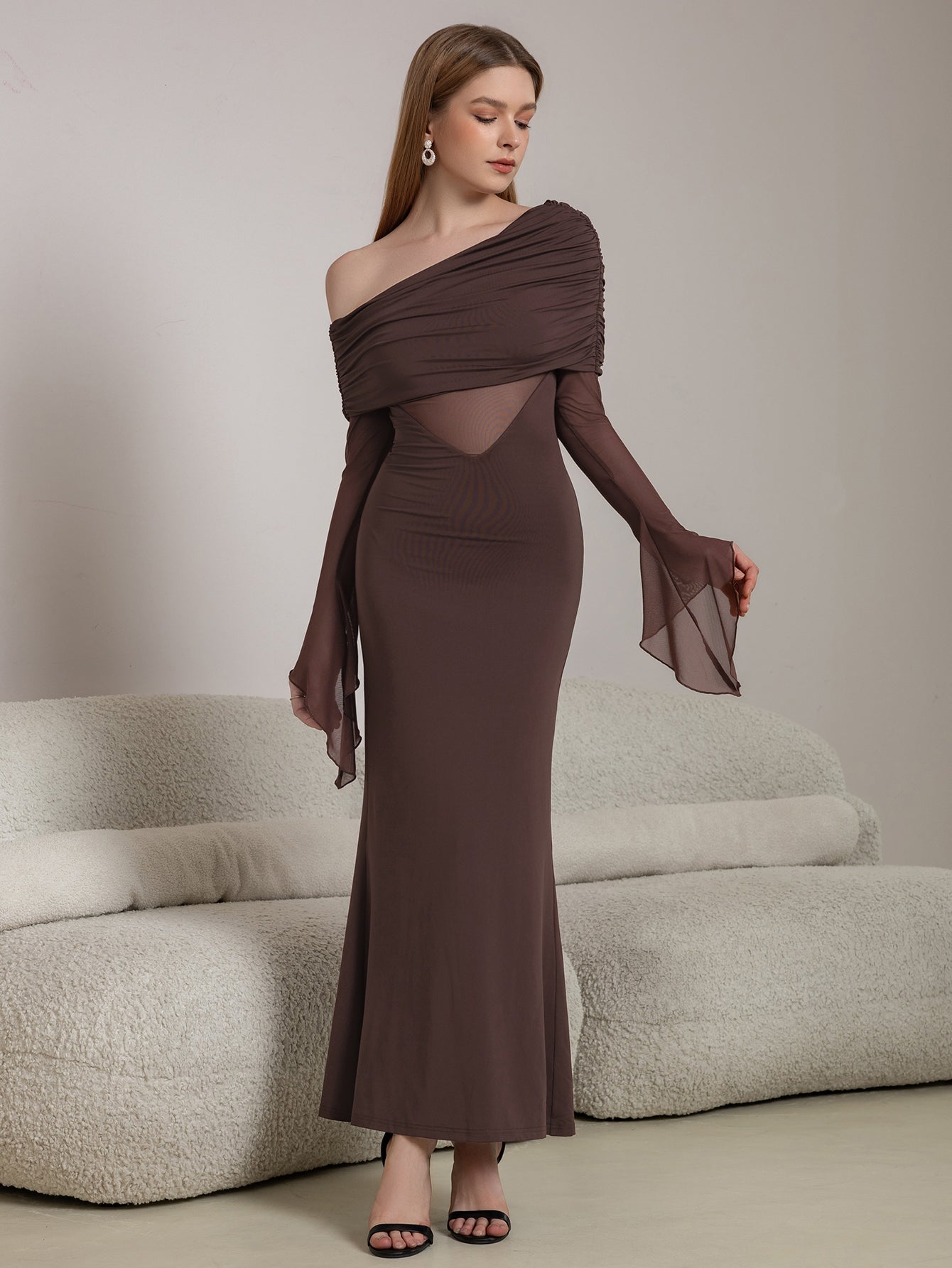 Front view of a woman in a brown off-the-shoulder dress with sheer long sleeves
