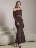 Model posing in a long brown ruched dress with sheer elements