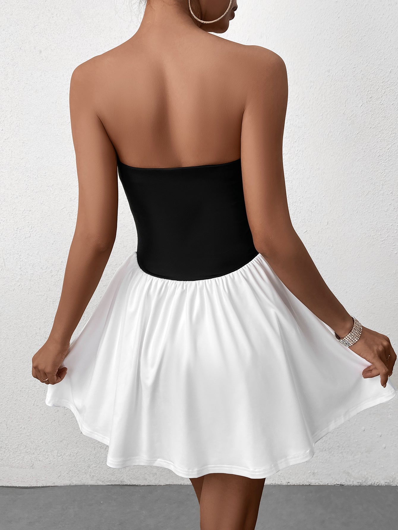 Woman wearing a black strapless bodice with a white gathered skirt, back view