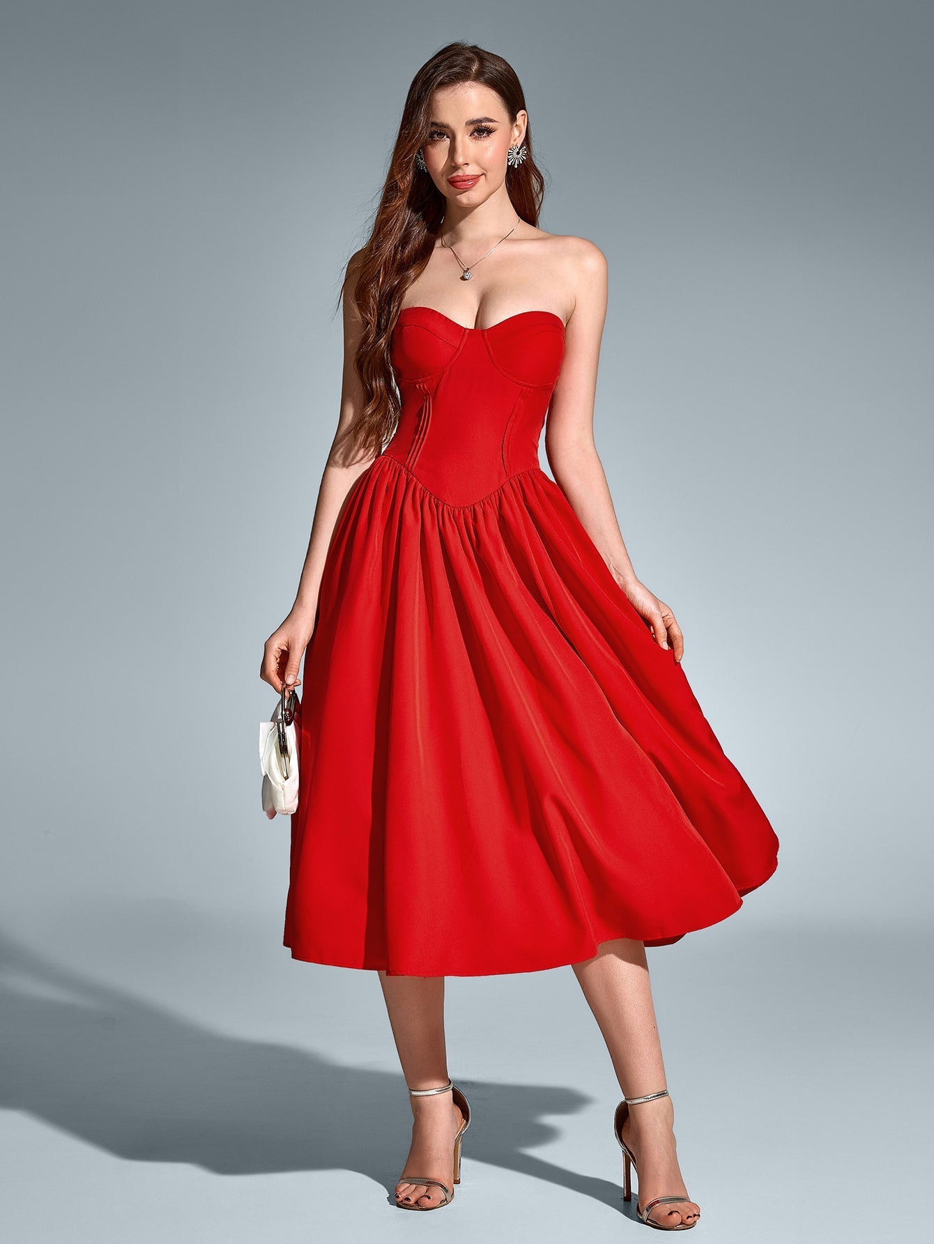 Full-body shot of a woman in a red strapless satin midi dress with a sweetheart neckline and fitted waist.