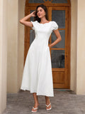 Woman in a white midi dress with puff sleeves, posing with one hand on her hip.