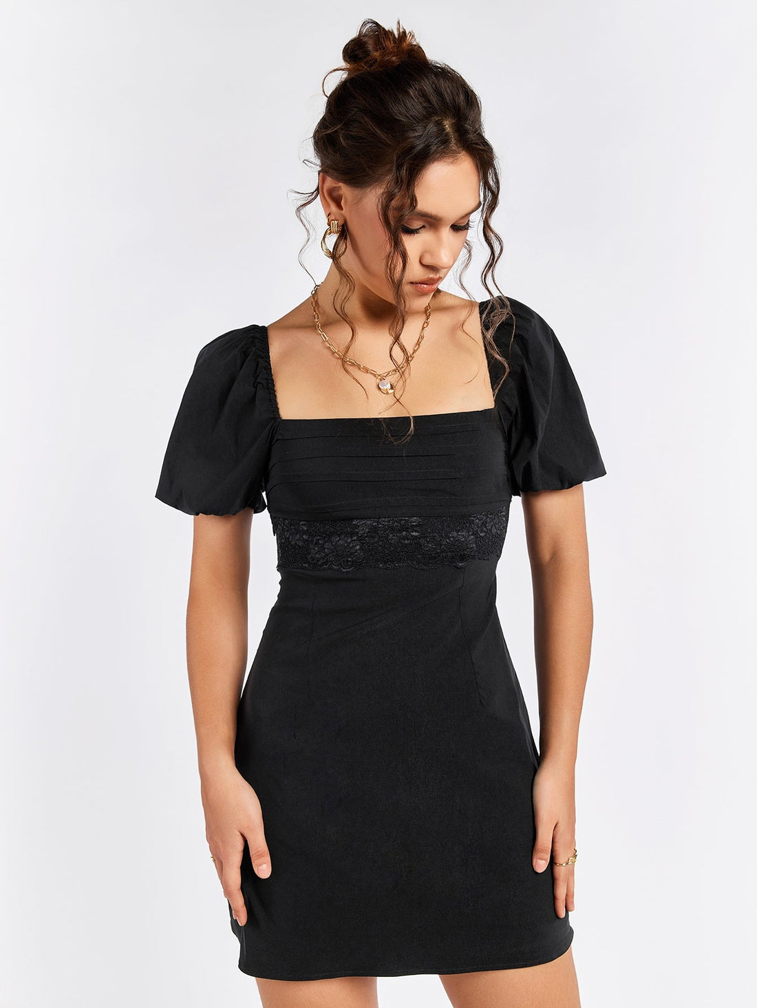 Woman wearing a black puff sleeve square neck dress with lace trim