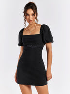 Front close-up of a black puff sleeve dress with square neckline and lace detail