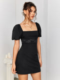 Woman in a black puff sleeve dress with lace trim standing by a column