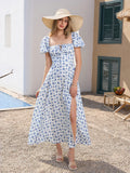 Full body shot of a woman in a floral print maxi dress and a straw hat