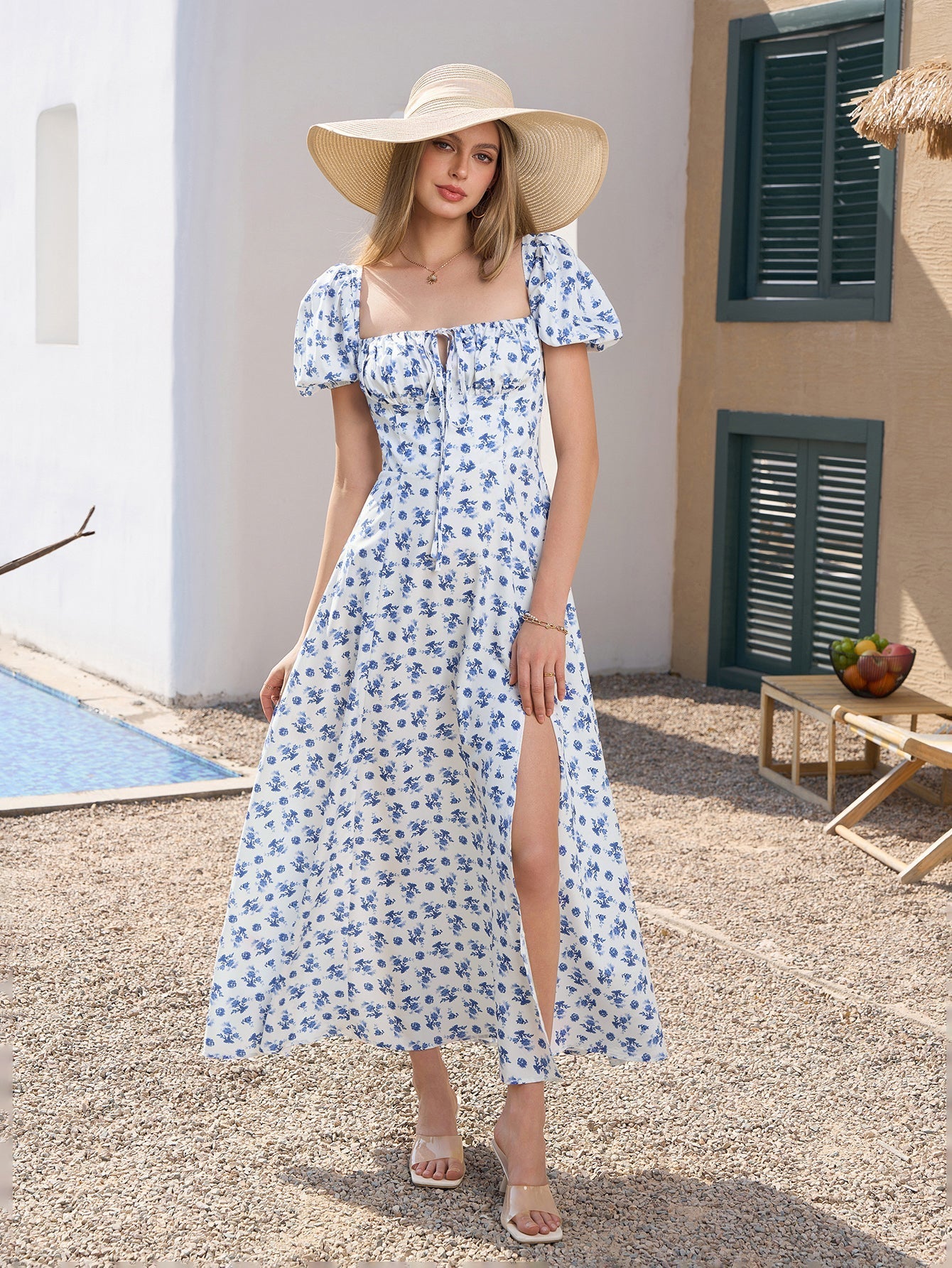 Full body shot of a woman in a floral print maxi dress and a straw hat
