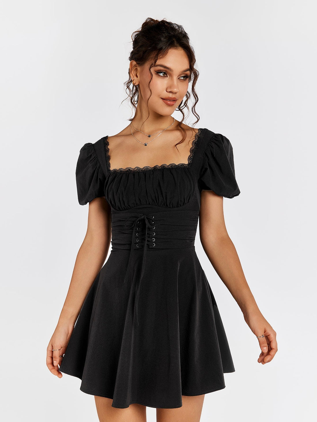 Woman wearing a black short puff sleeve square neck dress with ruched bodice and corset lacing.