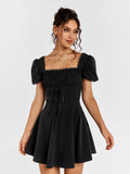 Woman wearing a black short puff sleeve square neck dress with ruched bodice and corset lacing.