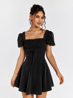 Woman wearing a black short puff sleeve square neck dress with ruched bodice and corset lacing.