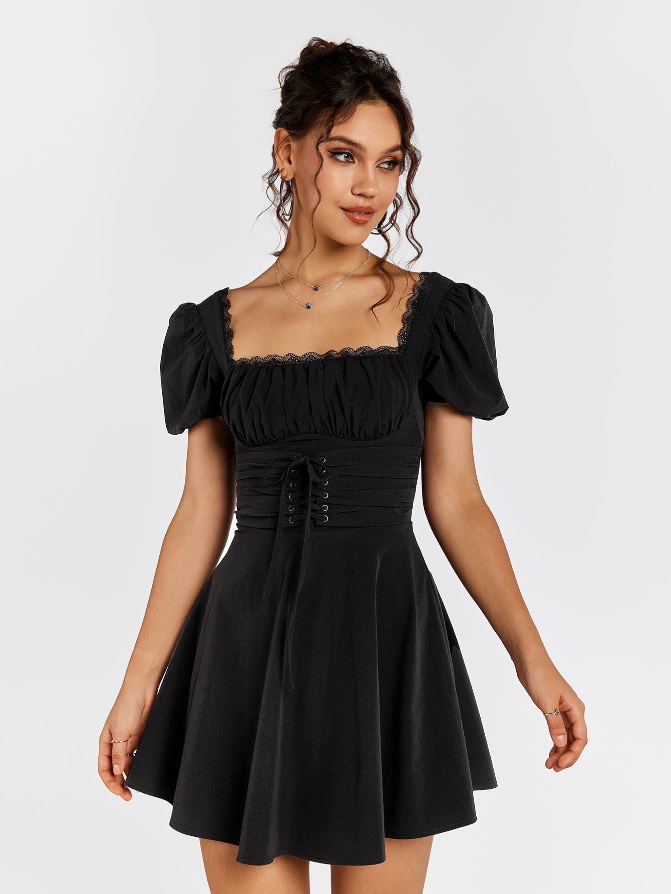Woman wearing a black short puff sleeve square neck dress with ruched bodice and corset lacing.