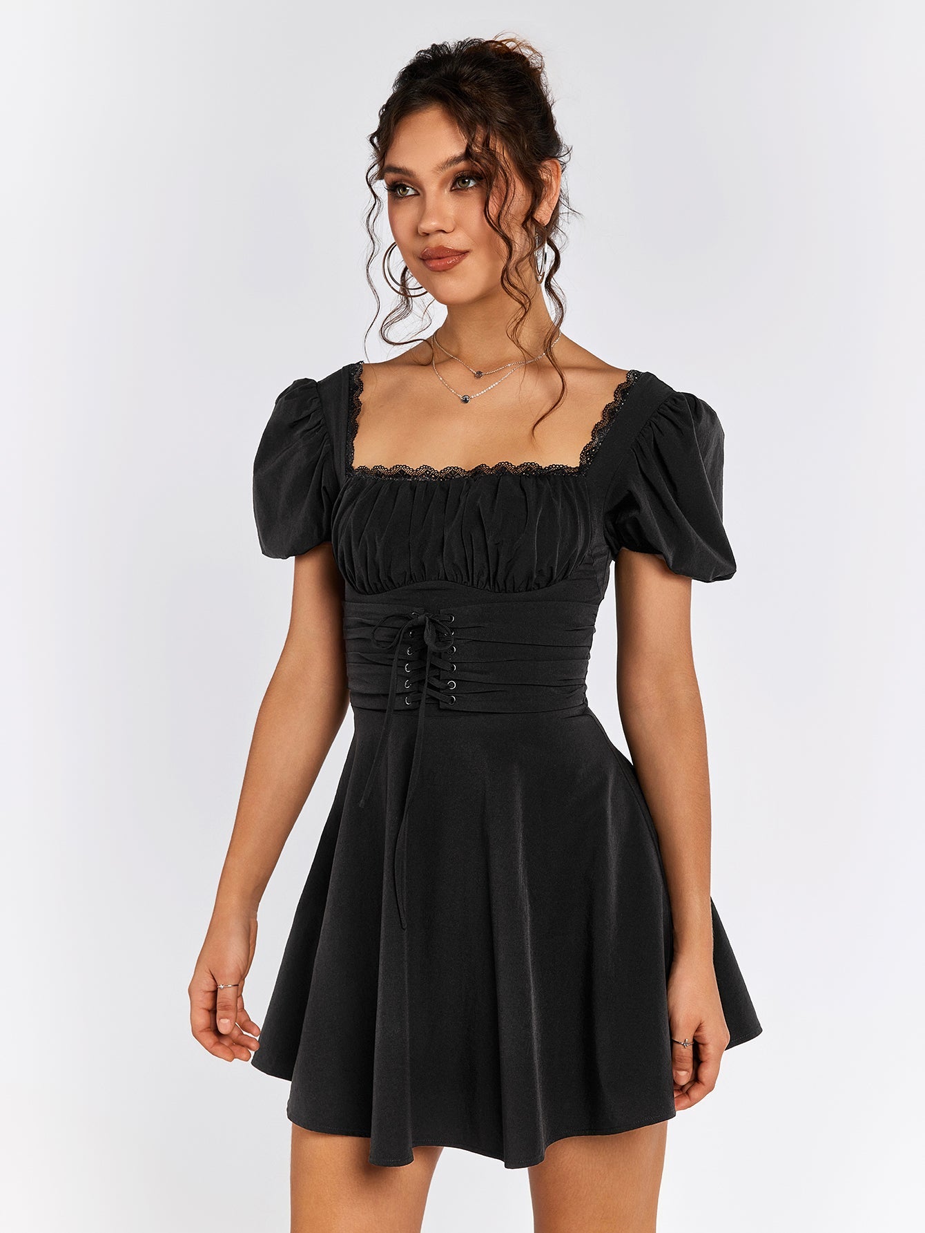 Front view of a woman in a black short puff sleeve square neck dress with a cinched waist.