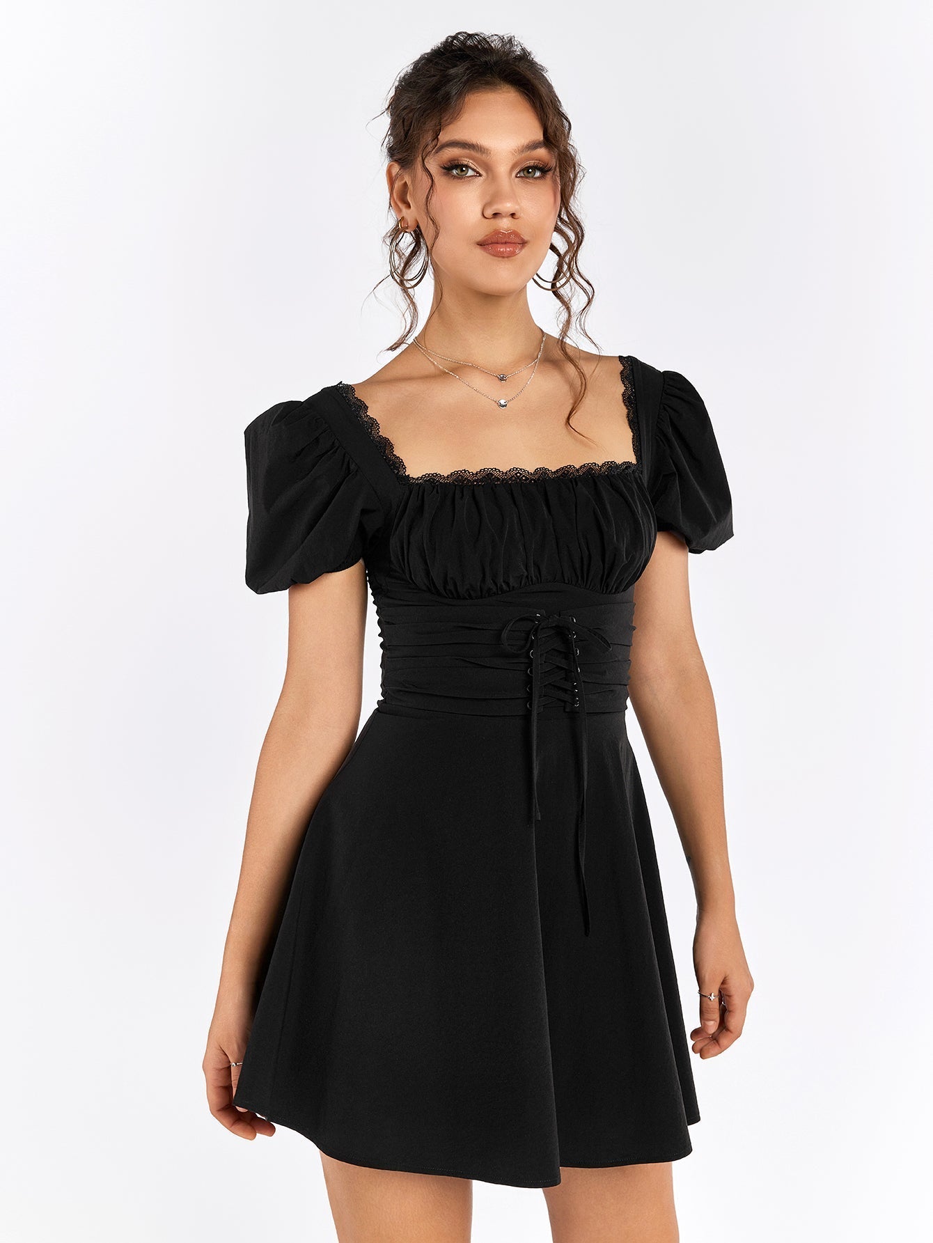 Woman in a black short puff sleeve square neck dress, showing the ruched bodice and corset lacing detail.