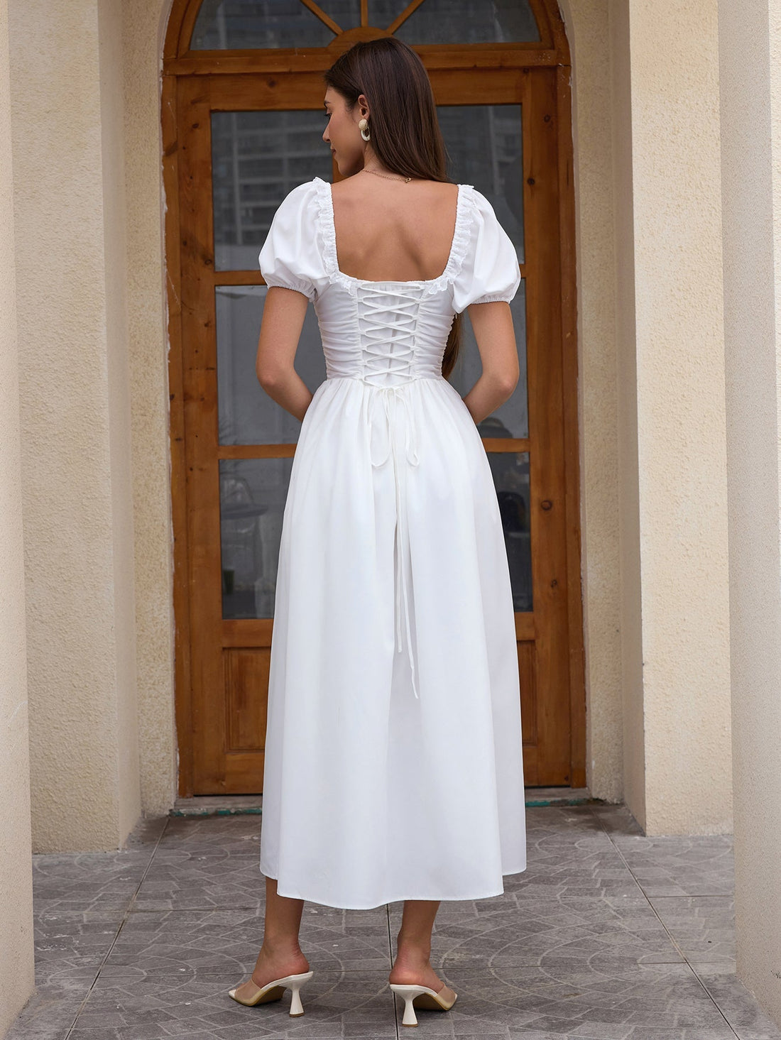 Woman wearing a white puff sleeve midi dress with a square neckline and corset bodice.