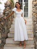 Woman smiling in a white puff sleeve midi dress with a square neckline and corset bodice, on outdoor stairs.