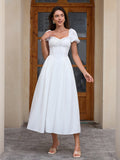 Woman wearing a white puff sleeve midi dress with a square neckline and corset bodice.