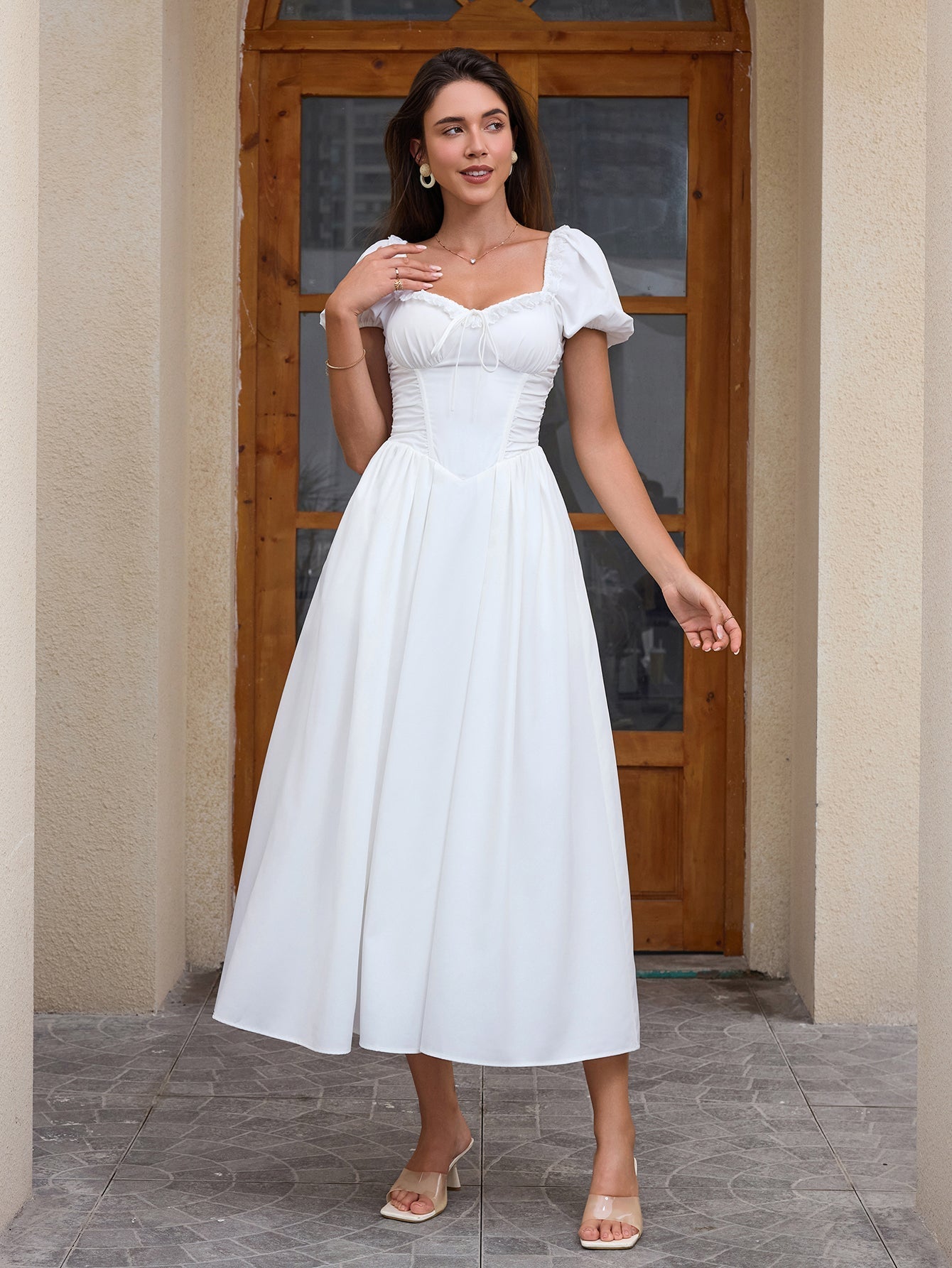 Woman wearing a white puff sleeve midi dress with a square neckline and corset bodice.