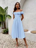 Woman in a light blue chiffon midi dress with a square neckline and cinched waist, standing outdoors.