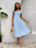Woman wearing a light blue chiffon fit and flare midi dress with puff sleeves and a square neckline.