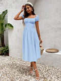 Woman in a light blue chiffon fit and flare dress with ruched bodice and puff sleeves, posing outdoors.