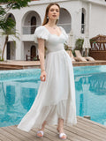 Woman in a white puff sleeve maxi dress with a sweetheart neckline and tiered hem posing by a pool.